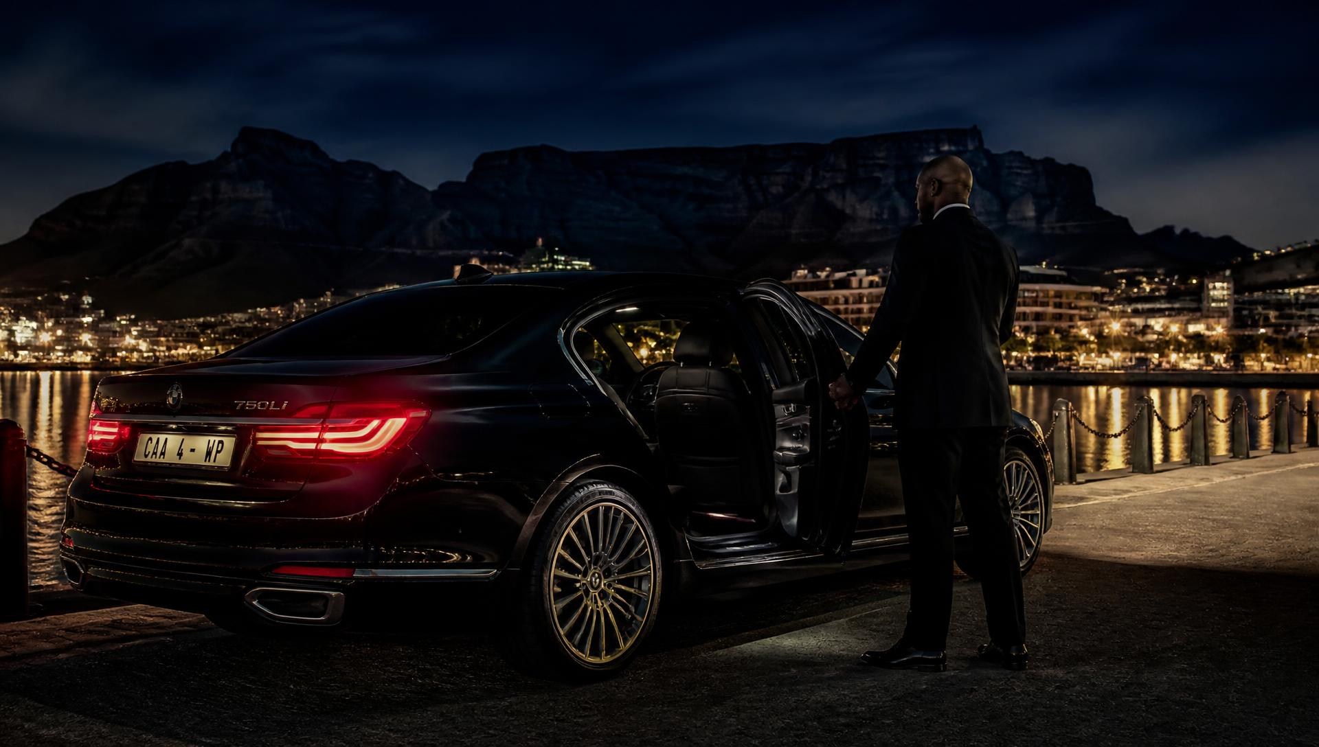 Chauffeur opening the door of a luxury sedan on the Cape Town waterfront at night